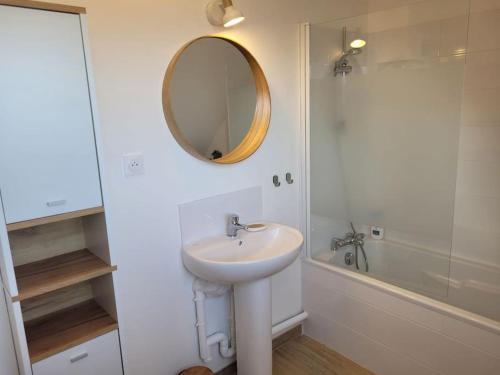 une salle de bain blanche avec un lavabo et un miroir dans l'établissement Coup de coeur à Pors Carn, à Penmarcʼh