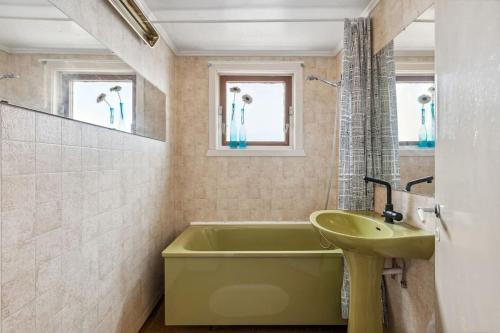 baño con bañera verde y lavamanos en Casa Melkhaugen, en Veiholmen