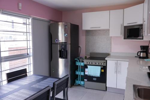 a kitchen with a stainless steel refrigerator and a table at Casa Pandora Hostel Women Only in San José