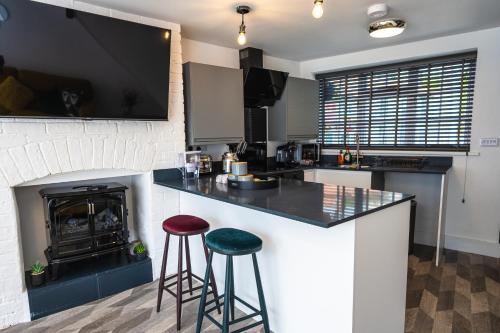 a kitchen with a counter with stools and a fireplace at Captivating 2-Bed House in Nettleham in Lincoln