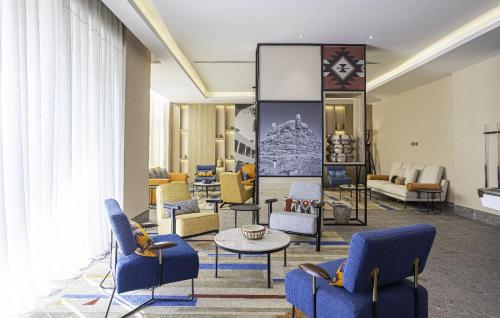 a lobby with blue chairs and a table in a room at Ewaa Express Hotel - Al Jouf in Sakakah