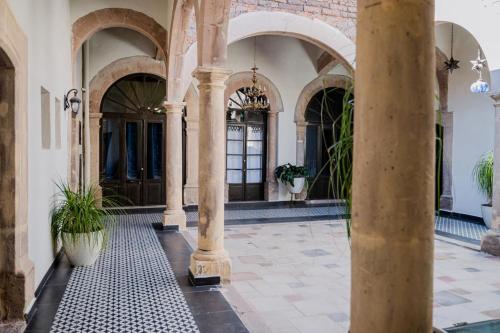 an arcade with pillars and plants in a building at Hotel Boutique Casona los Pavorreales in Durango