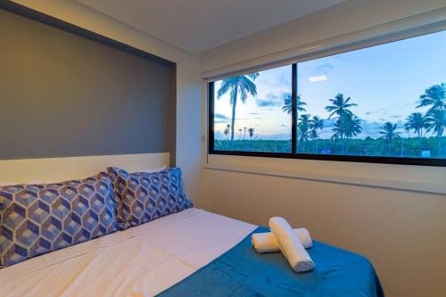 a bedroom with a bed and a window with palm trees at Marina do Cupe 302 in Porto De Galinhas