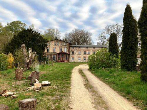 a dirt road in front of a large house at Alt Krassow Lakeside Retreat in Krassow