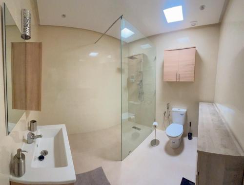 a bathroom with a shower and a toilet and a sink at Villa confortable et familiale de 458 m2 avec piscine privée au cœur du domaine des jardins de lAtlas à Marrakech in Sraghna
