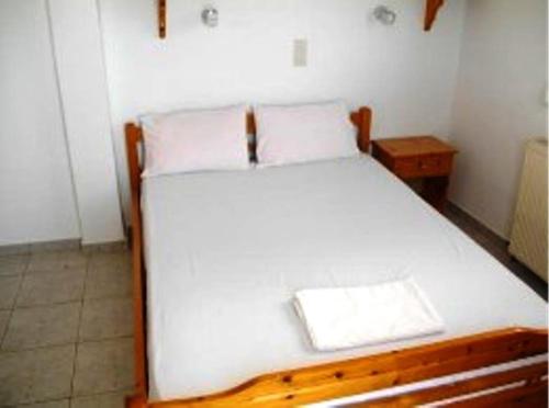1 dormitorio con 1 cama blanca con marco de madera en Pansion Panorama, en Patitiri