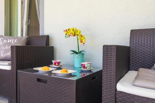 a table with plates of oranges and a vase with flowers at Apartment Tara with seaview in Krk