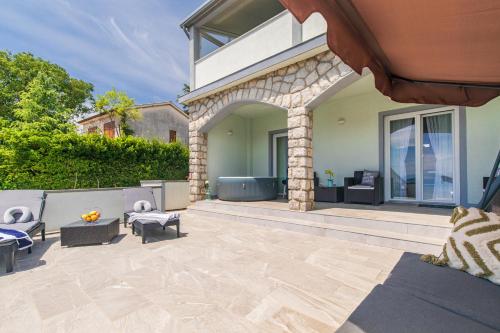 a patio with couches and chairs in front of a house at Apartment Tara with seaview in Krk