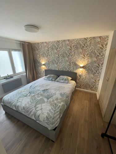 une chambre avec un lit avec un papier peint fleuri dans l'établissement Le cosy Lorientais, à Lorient