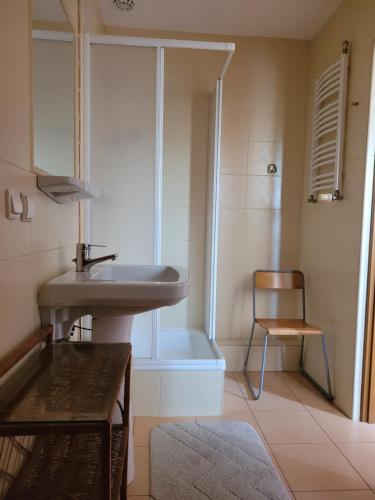 a bathroom with a sink and a shower and a chair at Pokoje Gościnne u Stasi in Mielno