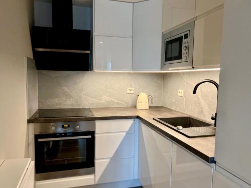 a kitchen with white cabinets and a sink and a microwave at Cozy Central Apartment in Ålesund in Ålesund