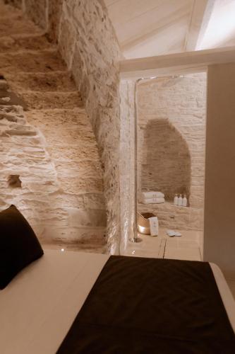 a bedroom with a brick wall and a bed in a room at Trullo Amiura B&B in Corato