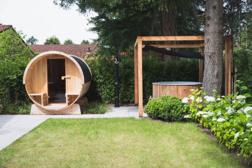 a wooden sauna in a garden with a tree at Bed en Wellness Groenrust Putten in Putten