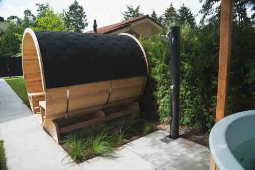 a wooden sauna sitting in a yard next to a hedge at Bed en Wellness Groenrust Putten in Putten