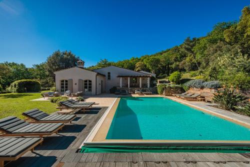 une piscine avec des chaises longues et une maison dans l'établissement Luxueuse Villa - Le paradis Terre et Mer, à Ramatuelle