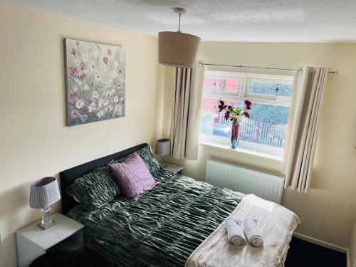 a bedroom with a bed and a vase of flowers in a window at Cozy 2 bed house oldham 10 miles to Manchester City centre wifi included in Oldham