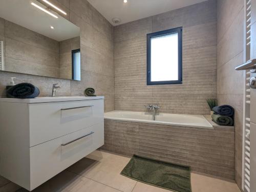 a bathroom with a tub and a sink and a mirror at Maison TESLA aéroport gare cnpe rte Golf de Lyon in Jons