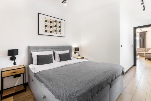 a white bedroom with a large bed and a chair at Apartamenty Larice - balia lub sauna sesja gratis ten weekend, morsowanie w basenie in Świeradów-Zdrój