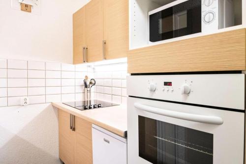 une cuisine avec une cuisinière et un micro-ondes dans l'établissement Résidence Le Plein Sud - 2 pièces 5/6 pers. PLAGNE VILLAGES - LE PLEIN SUD - Wifi inclus MAE-1804, à Aime La Plagne