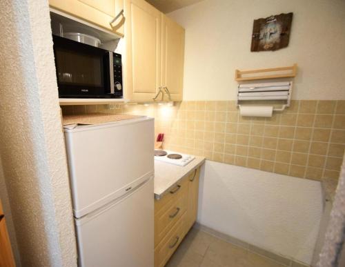 La cuisine est équipée d'un réfrigérateur blanc et d'un four micro-ondes. dans l'établissement Résidence Les Soldanelles - Studio divisible 4 pers - LES SOLDANELLES - PLAGNE VILLAGES MAE-6054, à Aime La Plagne