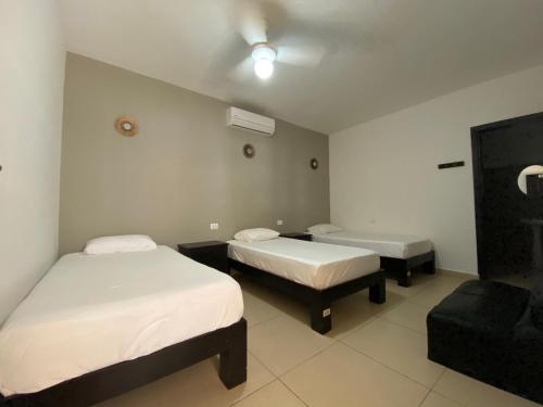 a hotel room with two beds and a chair at We playa Hotel in Playa del Carmen