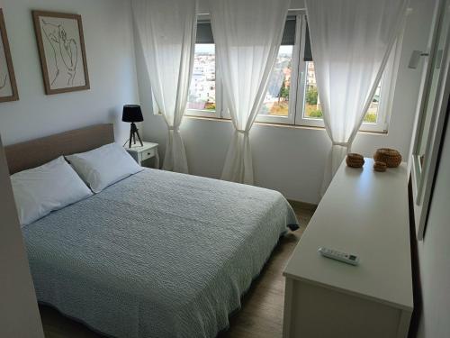 een slaapkamer met een bed en twee ramen bij Apartamento 90m2 com vista mar - Albufeira in Albufeira