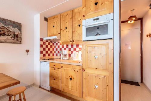 - une cuisine avec des placards en bois et un four micro-ondes dans l'établissement Résidence La Taiga - 2 Pièces 5/6 pers - LA TAIGA - PLAGNE CENTRE MAE-5444, à Aime La Plagne