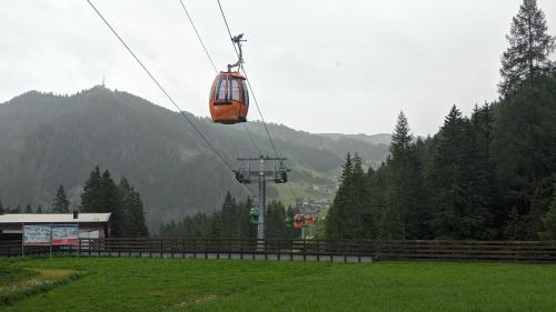an orange cable car flying over a green field at Garni Diamant in Colfosco