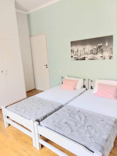 two beds in a room with white walls and pink pillows at Φωτεινό δίκλινο δωμάτιο με θέα! in Athens