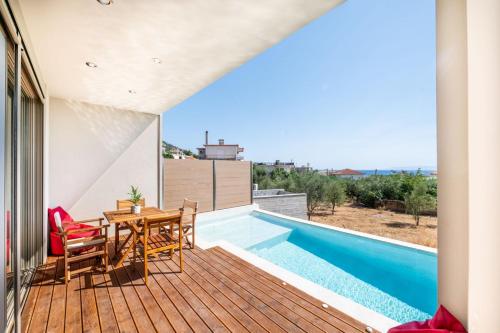 a balcony with a table and chairs and a swimming pool at Petradi Suites in Kalamata