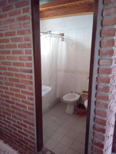 a bathroom with a brick wall and a toilet at JONATAN II Bed & Breakfast in Mina Clavero