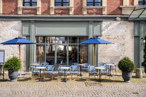 a group of tables and chairs with blue umbrellas at L'INVITATION AU VOYAGE - Hôtel & Spa in Honfleur