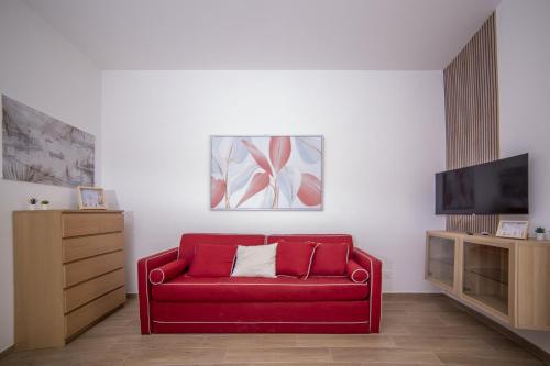 Una sala de estar con un sofá rojo y un televisor de pantalla plana. en La portineria guest house, en Bari