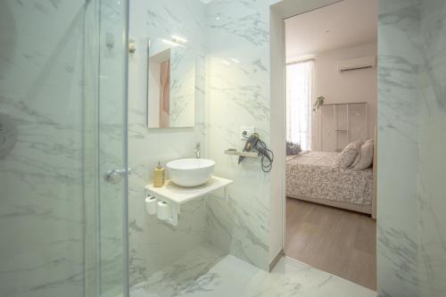 Un baño con lavabo y ducha de cristal. en La portineria guest house, en Bari