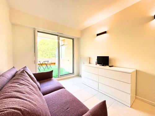 un salon avec un canapé violet et une télévision dans l'établissement Studio vue mer - Clim, Piscine & restaurant, à Nice