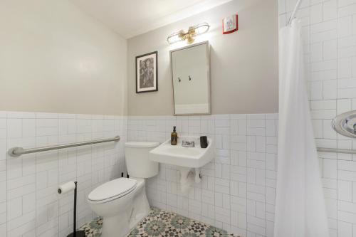 a white bathroom with a toilet and a sink at Tower Hotel Little Havana in Miami