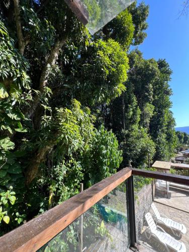 a wooden deck with chairs and a tree at Yannai Chalé Praia in Ilhabela