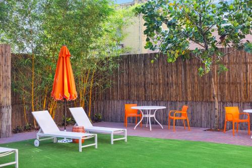 a patio with chairs and an orange umbrella and a table and chairs at Tower Hotel Little Havana in Miami