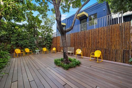 a wooden deck with yellow chairs and a tree at Tower Hotel Little Havana in Miami
