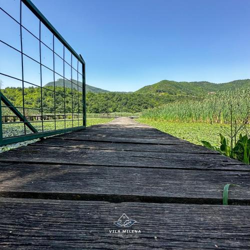a wooden boardwalk with a fence and mountains in the background at Vila Milena in Međuvršje