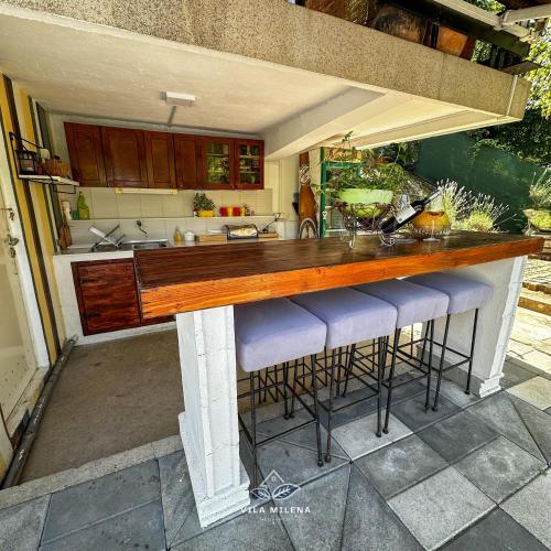 a kitchen with a large wooden counter with stools at Vila Milena in Međuvršje