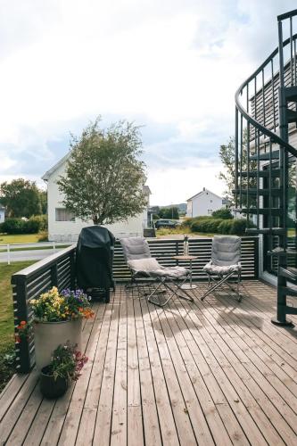 a wooden deck with two chairs and flowers on it at Modern house 5 bedrooms 2 baths sentral in Bodø