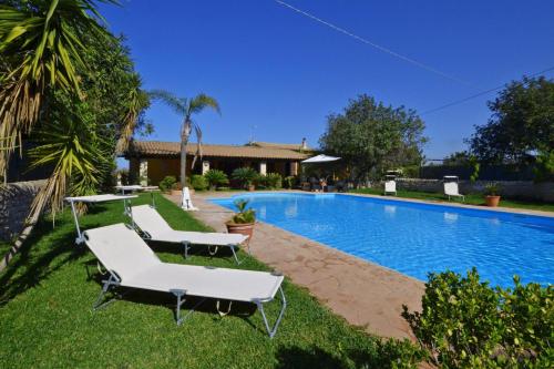 a swimming pool with two white lounge chairs next to it at Villa Torres - Happy Rentals in Scicli