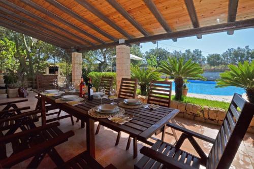 a wooden table and chairs on a patio with a pool at Villa Torres - Happy Rentals in Scicli