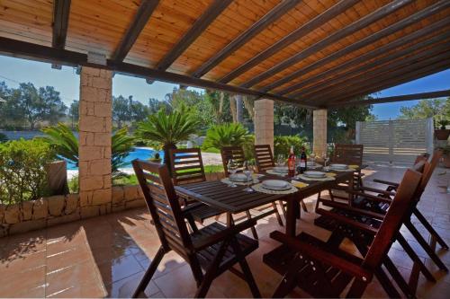 a wooden table and chairs under a wooden pergola at Villa Torres - Happy Rentals in Scicli