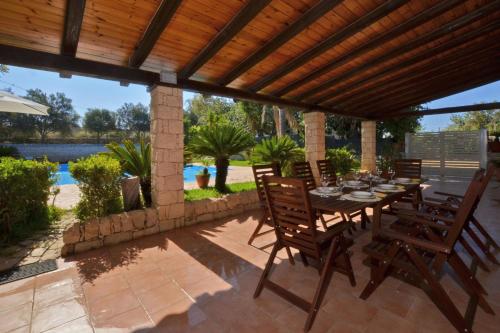 a patio with a table and chairs under a wooden pergola at Villa Torres - Happy Rentals in Scicli