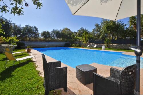 a swimming pool with chairs and an umbrella at Villa Torres - Happy Rentals in Scicli
