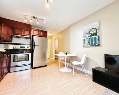 a kitchen with a table and a stainless steel refrigerator at Cozy 1bedroom Suite in Vancouver Westside in Vancouver