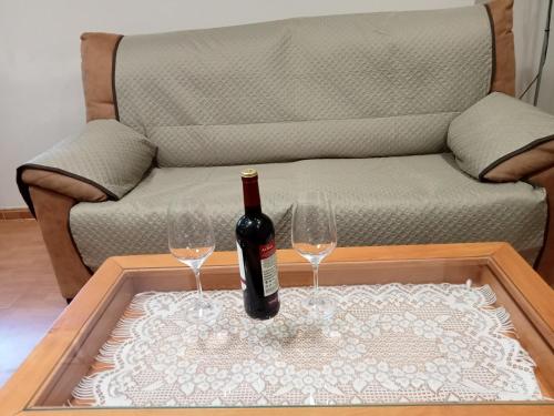 a bottle of wine and two glasses on a coffee table at Flor de Olivo in Puente de Génave