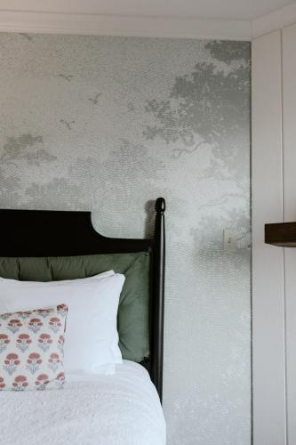 a bedroom with a white bed and a gray wall at Fireside Inn on Moonstone Beach in Cambria